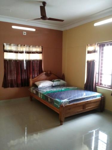 a bedroom with a bed in a room with windows at Sowparnika N.V Nagar Peroorkada in Trivandrum