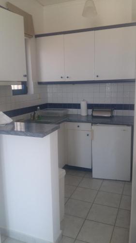 a kitchen with white cabinets and a white refrigerator at Vivlos. Maisonette with View in Vívlos