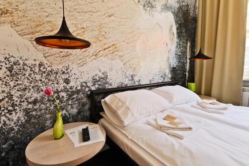 a bed with a table and a vase with a flower at Sleep in Hostel & Apartments Stary Rynek in Poznań