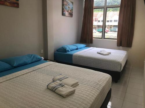 Dos camas en una habitación de hotel con toallas encima. en Best Seven Motel, en Kuah