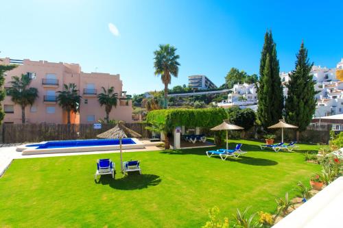 a yard with lawn chairs and umbrellas at Apartamentos Turisticos Almoraide Suites in Nerja