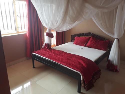 um quarto com uma cama com almofadas vermelhas e cortinas em Brisk Hotel Triangle em Jinja