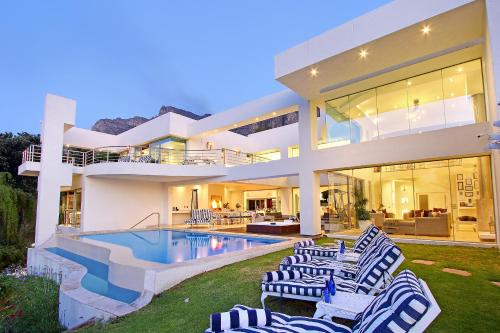 een groot huis met een zwembad en ligstoelen bij Hollywood Mansion & Spa Camps Bay in Kaapstad