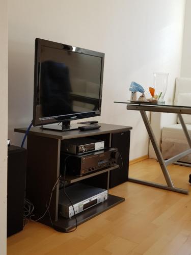 a flat screen tv on a stand with a table at villa high ceiling 2 bedrooms in Troisdorf