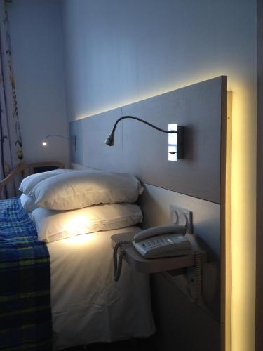 a bedroom with a bed with a nightstand next to it at Hotel Restaurant Le Dauphin et Le Spa du Prieuré in Caen