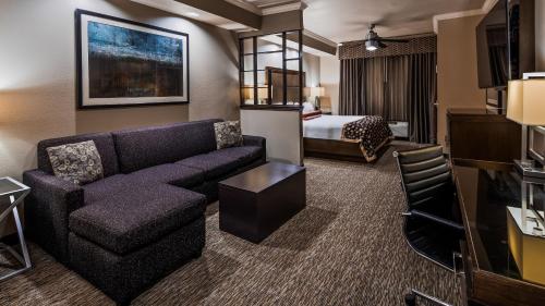 a hotel room with a couch and a bed at Best Western Premier Crown Chase Inn & Suites in Denton