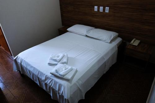 ein Schlafzimmer mit einem weißen Bett und Handtüchern darauf in der Unterkunft Hotel Almanara Cuiabá-Mato Grosso-Brasil in Cuiabá