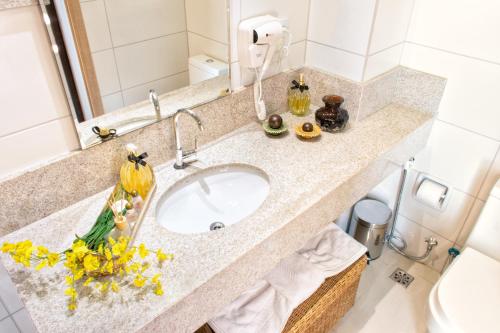 eine Badezimmertheke mit Waschbecken und Blumen darauf in der Unterkunft Rodoserv Hotel in Pardinho