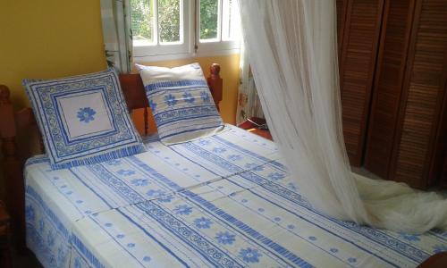 een bed met blauwe en witte lakens en kussens bij La Belle Créole in Sainte-Anne