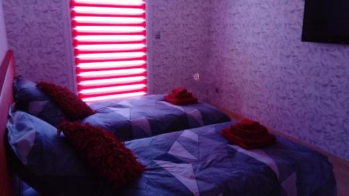 two beds in a room with purple walls and a window at L'Esthélio in Ambérieu-en-Bugey