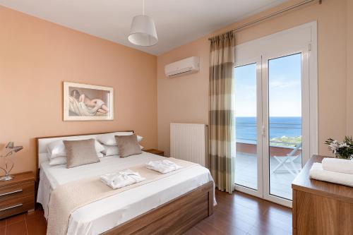 a bedroom with a bed with a view of the ocean at Anemolia Seaview Villa, with private Pool & Garden, By ThinkVilla in Gerani