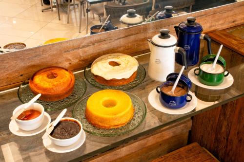 a counter with different types of cakes and cups of coffee at Rodoserv Hotel in Pardinho