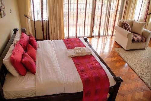 a large bed with red pillows in a room at Orchid Homes, Gigiri in Nairobi