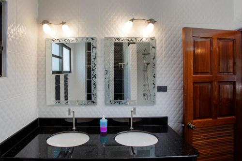 a bathroom with two sinks and two mirrors at Ya Nui Resort - SHA EXTRA Plus in Rawai Beach