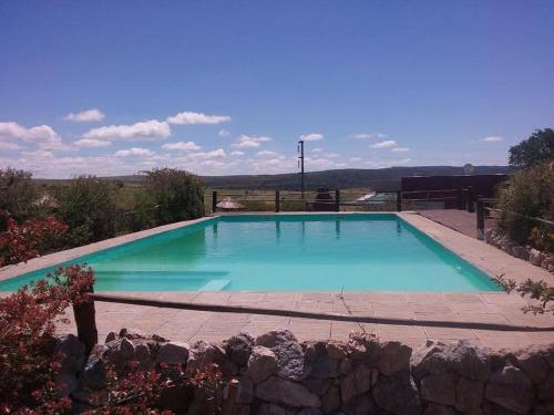 a large blue swimming pool with a rock wall at Acceso Viejo Casas de Campo in La Cumbre