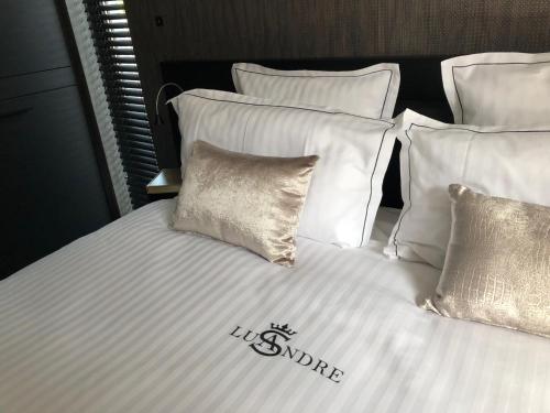 ein Bett mit weißer Bettwäsche und Kissen mit den Worten "wir quadratisch" in der Unterkunft Lusandre in Olen