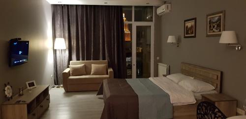 a bedroom with a bed and a chair and a couch at Luxury Room in Batumi