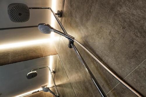 a shower in a bathroom with a light on the wall at Lusandre in Olen
