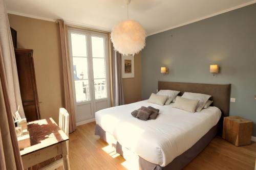 a bedroom with a large white bed and a large window at Hotel d'Angleterre Etretat in Étretat