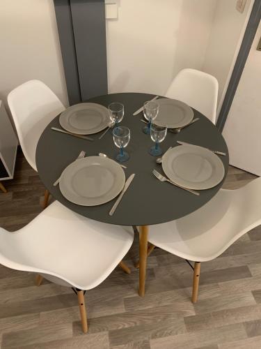 une table noire avec des chaises blanches, des assiettes et des verres dans l'établissement Avec JARDINET sans vis à vis Plein centre ville au RDC 350m de la plage, à Dieppe