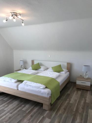 a bedroom with a large white bed with green sheets at Ferienhaus Heil in Neustadt an der Weinstraße