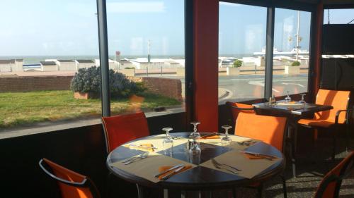 a restaurant with two tables and a view of the ocean at Hôtel De La Plage in Calais