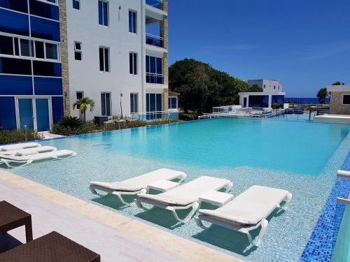 a large swimming pool with lounge chairs and a building at Koko and Suzy's ocean dream in Laguna del Higüero