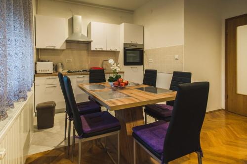 une cuisine avec une table en bois et des chaises violettes dans l'établissement Apartments "Pavić" near Zagreb Airport, à Velika Gorica