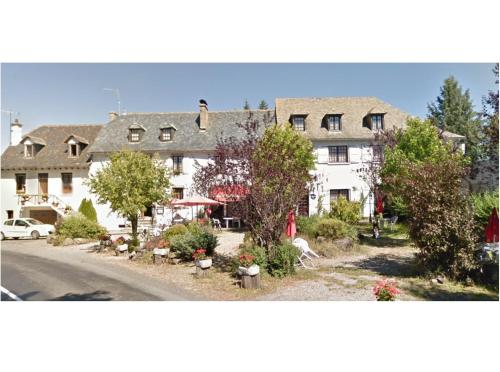 un grand bâtiment blanc avec des arbres et une rue dans l'établissement Auberge de Pont-la-Vieille, à Narnhac