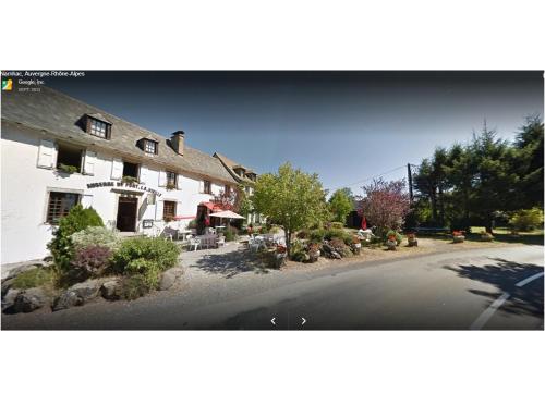 a large white building with a patio and a street at Auberge de Pont-la-Vieille in Narnhac