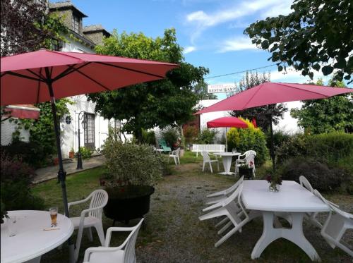 un groupe de tables et de chaises avec des parapluies rouges dans l'établissement Auberge de Pont-la-Vieille, à Narnhac