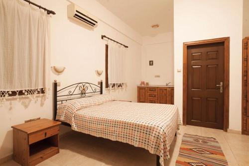 a bedroom with a bed and a wooden door at Glaro Garden Hotel in Rizokarpaso