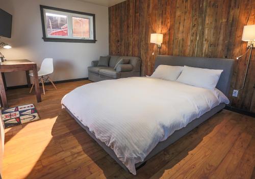 1 dormitorio con cama, silla y escritorio en Le Littoral Bistro Gourmand et Auberge, en Sainte-Anne-des-Monts
