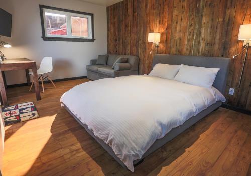 a bedroom with a bed and a chair and a desk at Le Littoral Bistro Gourmand et Auberge in Sainte-Anne-des-Monts