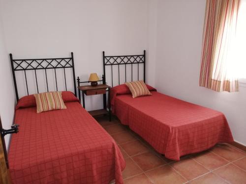 a room with two beds with red sheets and a table at CASA HACIENDA EL OLIVAR in El Bosque