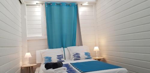 Un dormitorio con una cortina azul y una cama en Gîte Akwarel en Vieux-Habitants