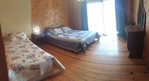 1 Schlafzimmer mit 2 Betten und Holzboden in der Unterkunft Casa Canelo in Algarrobo