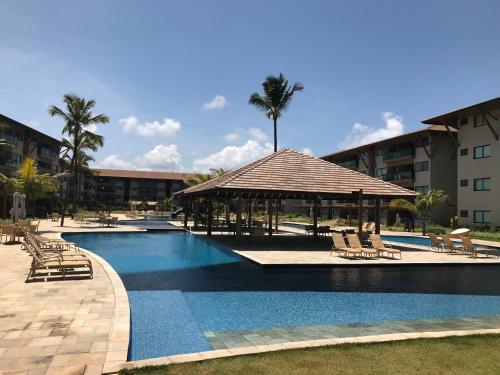 a large swimming pool with a gazebo and chairs at Apto luxo, Muro alto/Porto de galinhas, Polinésia in Porto De Galinhas