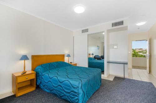 um quarto com uma cama azul e um espelho em Madison Ocean Breeze Apartments em Townsville