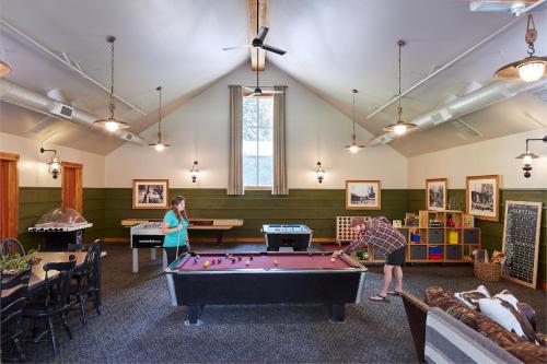 two people playing pool in a room with a pool table at Evergreen Lodge at Yosemite in Groveland
