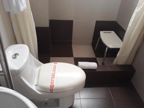 a small bathroom with a white toilet and a stool at Hotel Puerto Banana in El Guabo