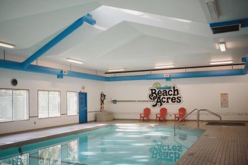 a swimming pool with red chairs and a sign on the wall at Beach Acres Resort in Parksville