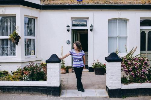 a woman standing outside of a white house at Rosslyn Court in Margate