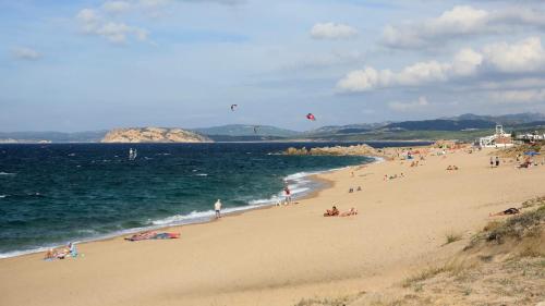 a group of people on a beach with people flying kites at Stazzo La Foci soluzioni vista Mare in Aglientu