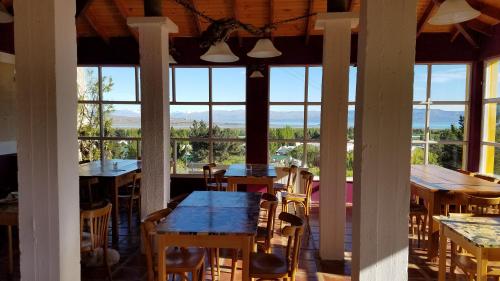 uma sala de jantar com mesas, cadeiras e janelas em South B&B El Calafate em El Calafate