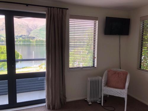 a room with a window with a chair and a television at Luxury on Lakeside in Wanaka