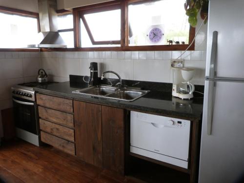 a kitchen with a sink and a refrigerator at Cabaña en la playa. ventanales y terraza al mar in Salinas 