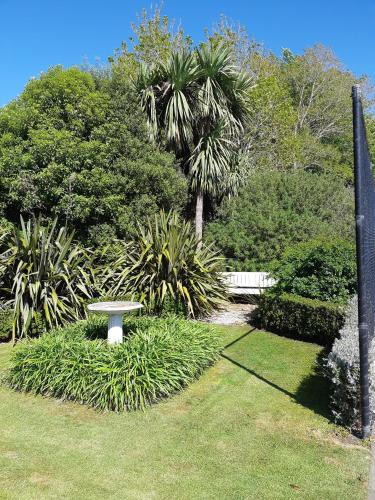 Un banco blanco en un parque con una palmera. en Maples on Harewood, en Christchurch