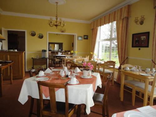 un comedor con mesas y sillas y una habitación con ventana en Alpine Guesthouse, en Dingle