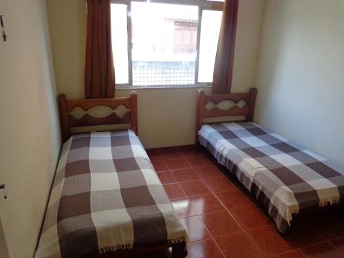 2 Betten in einem Zimmer mit Fenster in der Unterkunft Apto a 2 quadras da praia in Cabo Frio